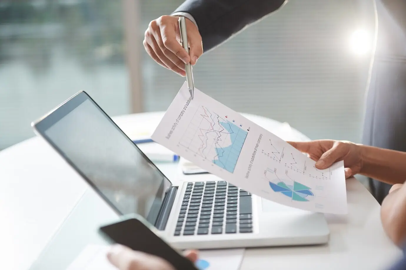 Équipe d’une entreprise moderne travaillant en coworking, utilisant des graphiques et un ordinateur portable au bureau.